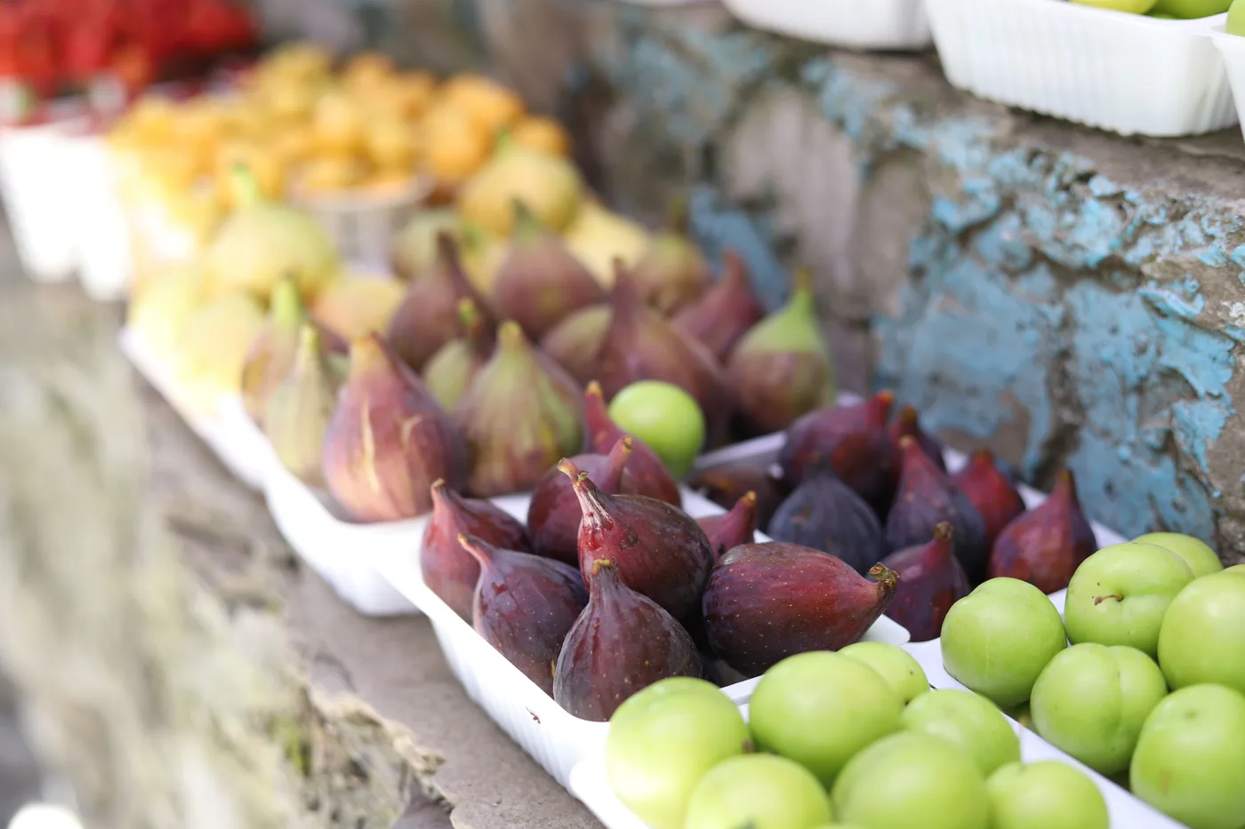 Barquettes de figues violettes et de prunes sur un étal de marché en août