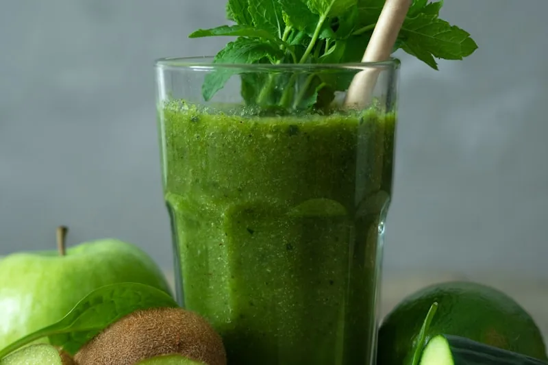 Personne tenant un verre de jus vert frais - rompre le jeûne en douceur avec des jus pressés à froid