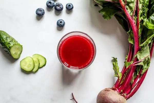 Jus de betterave rouge avec ingrédients frais sur table blanche