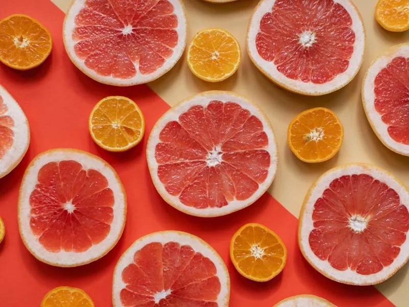 Tranches d'oranges et citrons frais sur fond orange et jaune vibrant, riches en vitamine C naturelle